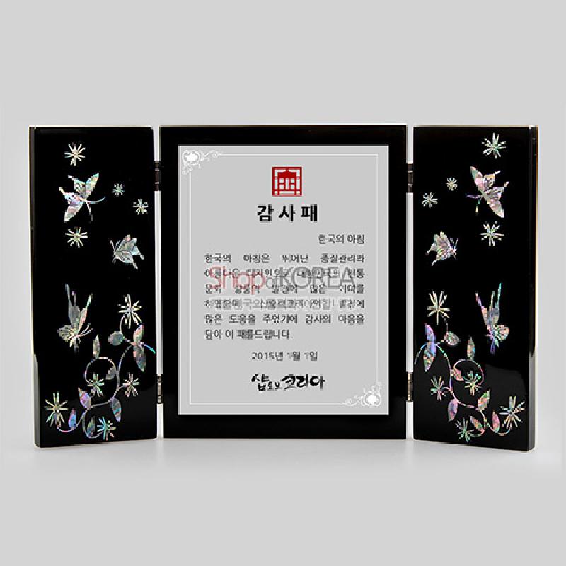 흑색 옻칠 바탕에 자개 상감 기법으로 꽃과 나비 문양을 표현한 3폭 접이식 상패.