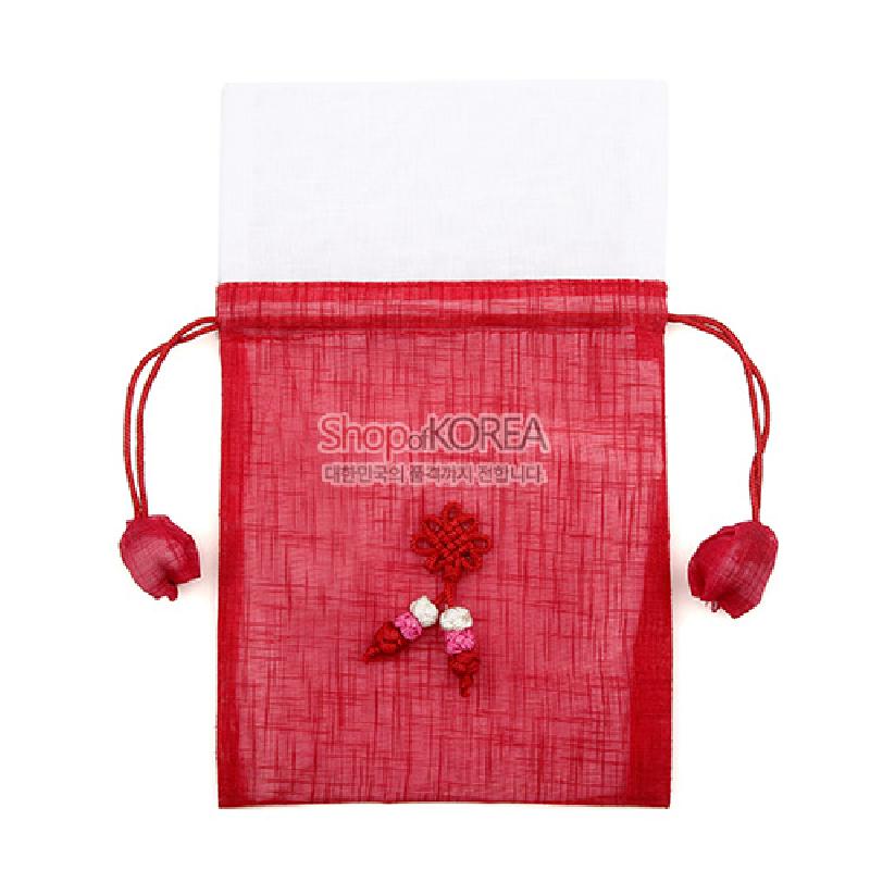 붉은색 모시 소재의 복주머니, 중앙의 전통 매듭 장식과 꽃 봉오리 매듭, 끈 끝 연꽃 모티브 장식이 돋보이는 디자인.