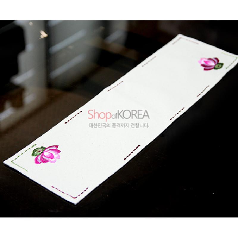 광목 소재의 아이보리 색 직사각 식탁보, 양 끝 연분홍 연꽃 문양과 가장자리 배색 스티치 장식이 돋보이는 디자인.