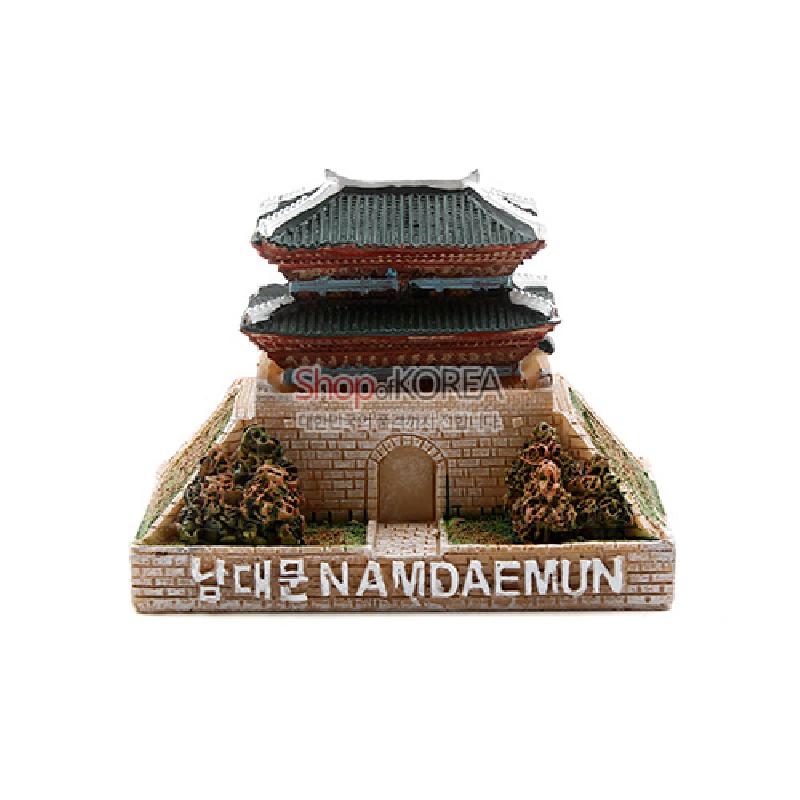 석고 재질로 제작된 남대문 형상의 미니어처 조형물, 녹색 기와와 갈색 성벽, 주변 수풀과 영문·한글 명각 장식.