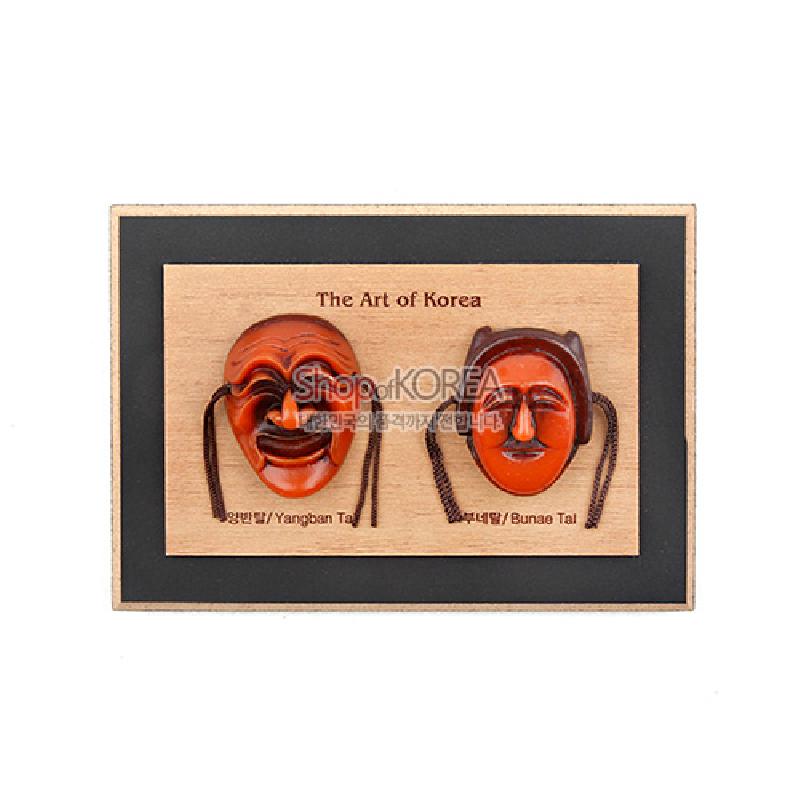 나무 판 위에 양반탈·부네탈을 입체적으로 배치한 목재 액자, 갈색 계열 채색과 끈 장식이 특징인 하회탈 장식 소품.