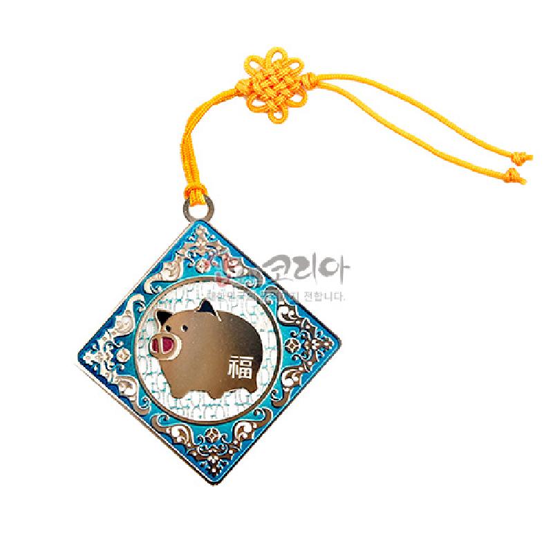 금속 재질의 정사각형 장식에 청색 에나멜과 돼지 십이지 문양, 중앙 한자 ‘복’ 글자와 노란 전통 매듭끈이 더해진 책갈피.