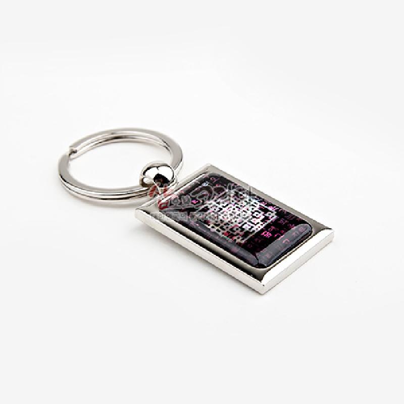 금속 테두리에 자개 느낌의 광택을 입힌 직사각 팬던트, 어두운 바탕에 시조문과 전통 문양을 붉은색·은색으로 배치한 열쇠고리.